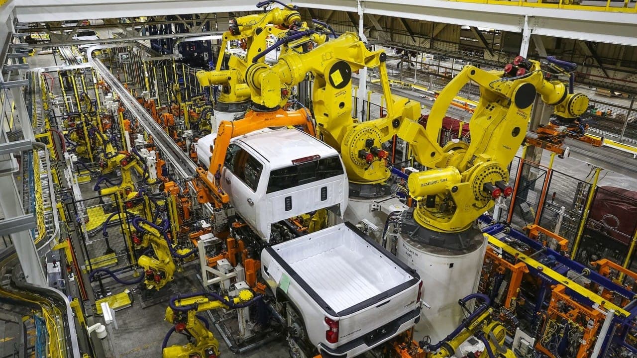Midwestern engineers working with early CAD systems in a heartland factory setting.